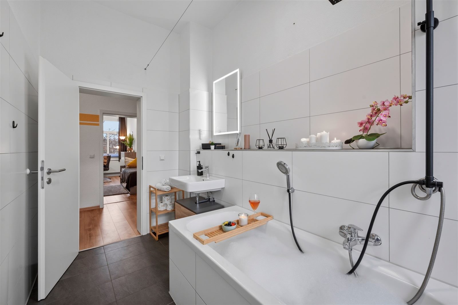 Geräumiges Bad mit Badewanne und Durchgang zum Schlafzimmer – hell und modern gefliest